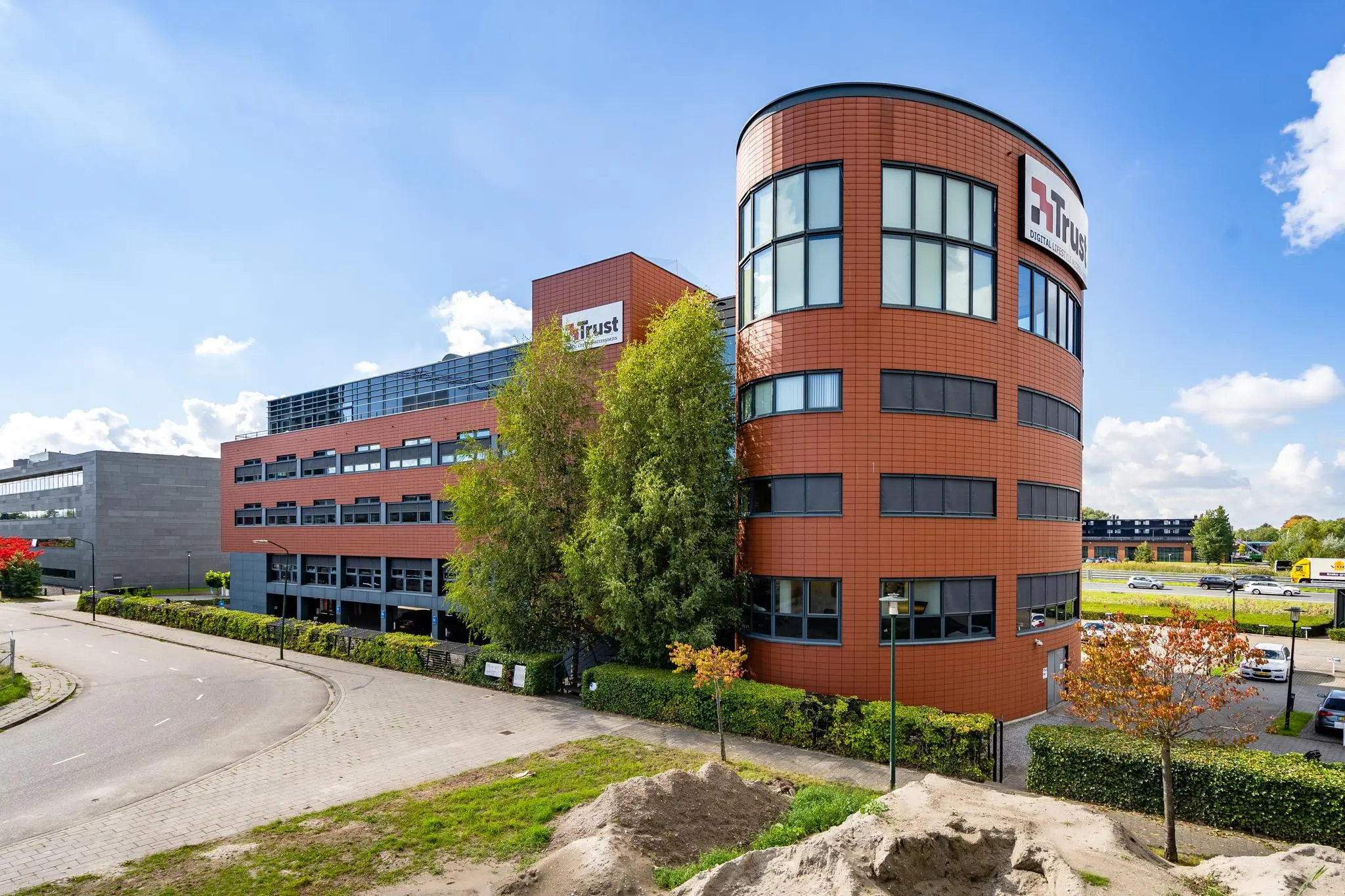 Kantoorgebouw van Trust aan de Laan van Barcelona met ronde voorkant en roodbruine gevel.